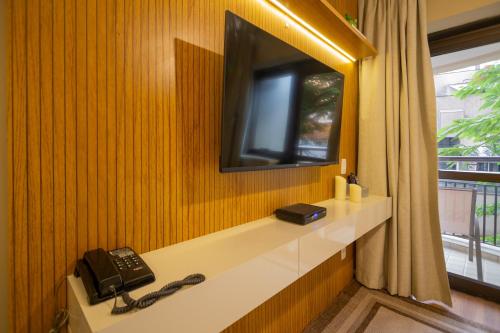 a room with a television and a telephone on a wall at The Capital Flat Itaim Bibi in Sao Paulo