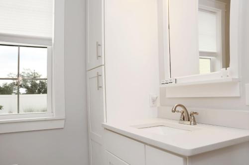 a white kitchen with a sink and a mirror at Reel Blessed by Pristine Properties Vacation Rentals in Saint Joe Beach