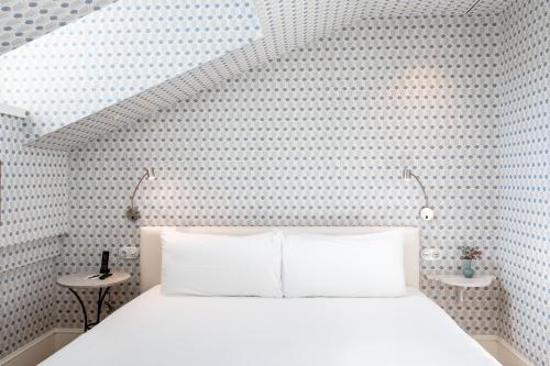 a bedroom with a white bed and a wall at Hotel Tayko Sevilla in Seville