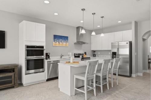 a kitchen with white cabinets and a counter with chairs at Fortebello Beachside 154 in Indian Harbour Beach