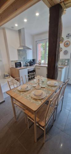 een keuken met een houten tafel met stoelen eromheen bij Charmant Cottage tout équipé 2 à 4 personnes in Hérin