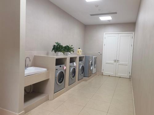 a laundry room with three washing machines and a sink at Pinxiayuan Apartment in Lvcheng Resort in Zhoushan