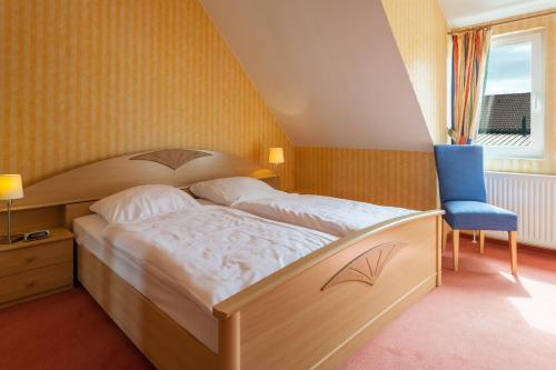 a bedroom with a large bed and a blue chair at Landhotel Zur Linde in Verden