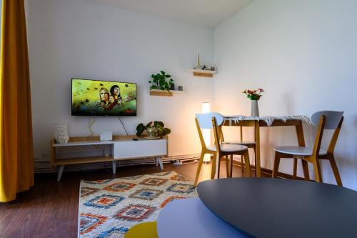uma sala de estar com uma mesa e uma televisão na parede em Apartament Corina cu parcare em Bistriţa