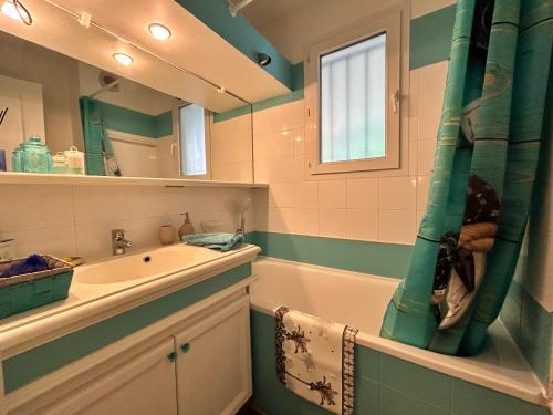 une salle de bain avec un lavabo, une baignoire et un miroir dans l'établissement Les Restanques vue mer Roses 1070 rez de jardin, à Grimaud