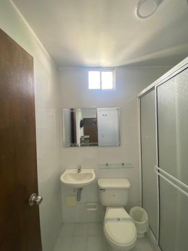 a white bathroom with a toilet and a sink at 22 Guest House in Santa Marta