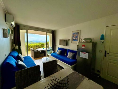 un salon avec un canapé bleu et une table dans l'établissement Les Restanques vue mer Roses 1070 rez de jardin, à Grimaud
