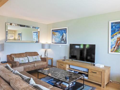 een woonkamer met een bank en een flatscreen-tv bij Apartment Roossi Apt- 1 by Interhome in Wengen