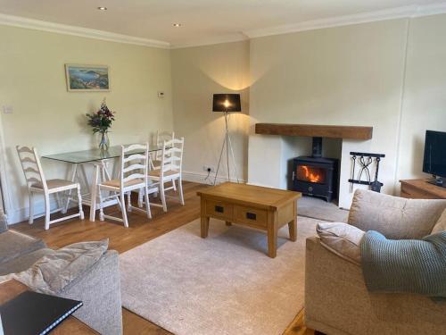 a living room with a table and a fireplace at Beautiful stone cottage in peaceful village in Richmond