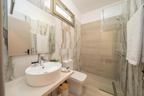 a white bathroom with a sink and a shower at Nicole Studios in Ayia Evfimia