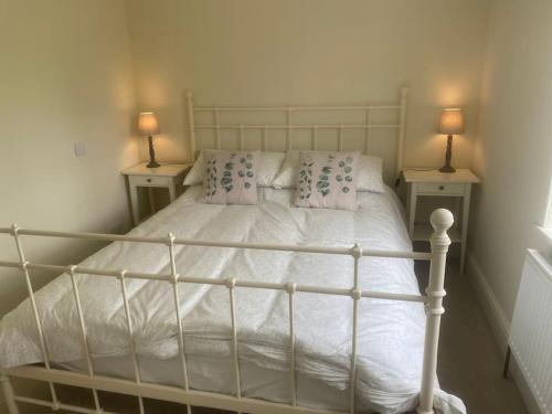 a bedroom with a white bed with two tables at Beautiful stone cottage in peaceful village in Richmond