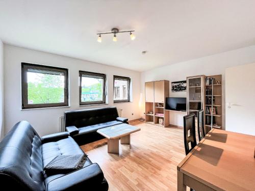 a living room with a black leather couch and a table at Apartment Ferienapartments Adenau-3 by Interhome in Adenau