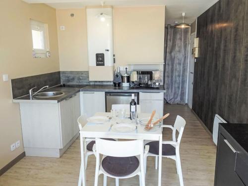 a kitchen with a white table and chairs in a room at Apartment Les Romarins by Interhome in Narbonne-Plage