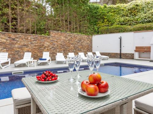 a table with wine glasses and fruit on it next to a pool at Villa Palmbeach by Interhome in Lloret de Mar