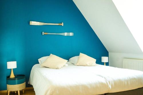a bedroom with a white bed with a blue wall at villa port l epine, 4 chambres, vue mer in Trélévern