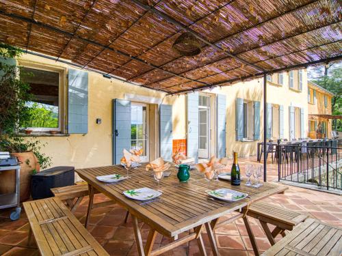 une table en bois sur une terrasse avec une bouteille de vin dans l'établissement Holiday Home Le Mas by Interhome, à Besse-sur-Issole