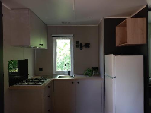 a kitchen with a sink and a white refrigerator at Camping Villaggio Il Collaccio in Preci