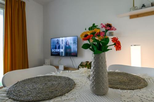 um vaso com flores sobre uma mesa com uma televisão em Apartament Corina cu parcare em Bistriţa