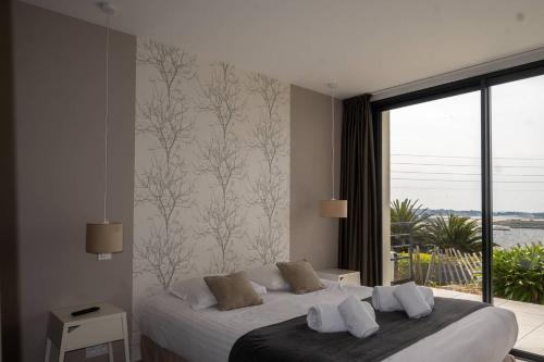 une chambre avec un lit avec une grande fenêtre dans l'établissement agapanthes, Facing the sea, indoor pool, à Pleumeur-Bodou