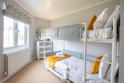 Un dormitorio con dos literas y una ventana. en Windrush Lake 41, Kingfisher House, en South Cerney