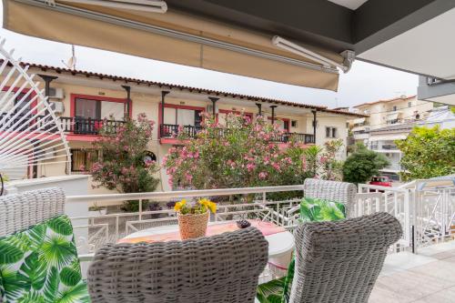 a table and chairs on a balcony with flowers at Family Inn Apartments&suites in Neos Marmaras