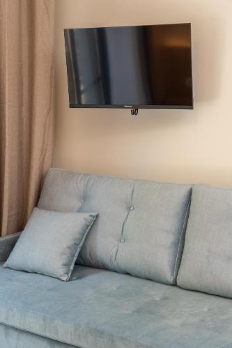 a couch with two pillows sitting under a television at Nicole Studios in Ayia Evfimia