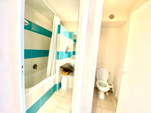 a bathroom with a toilet and a tub and a sink at Hôtel Bellevue Cap d'Agde in Cap d'Agde