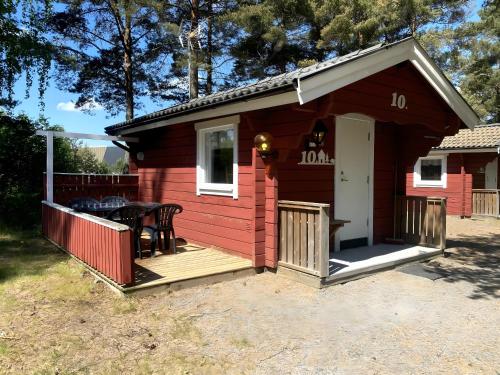 een rode hut met een tafel op een terras bij Hyltena Stugby in Jönköping
