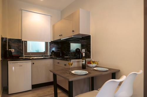 a kitchen with a table and white cabinets at Nicole Studios in Ayia Evfimia