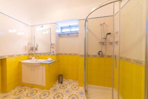 a yellow bathroom with a sink and a shower at Cerasella B&B in Ischia