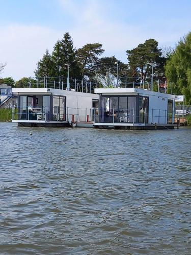 two houses are sitting on the water at ARKA 1 domki na wodzie w Mielnie, rower wodny, bezpłatny WIFI, Parking in Mielno