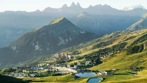 a town on a hill with mountains in the background at Le Col Panoramic in La Toussuire