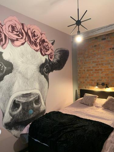 a mural of a cow with roses on its head next to a bed at Siedlisko Kępina Zdrój in Ostrów