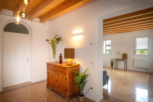 a living room with a wooden dresser with flowers on it at Barchessa Cappelletto in Torre di Mosto