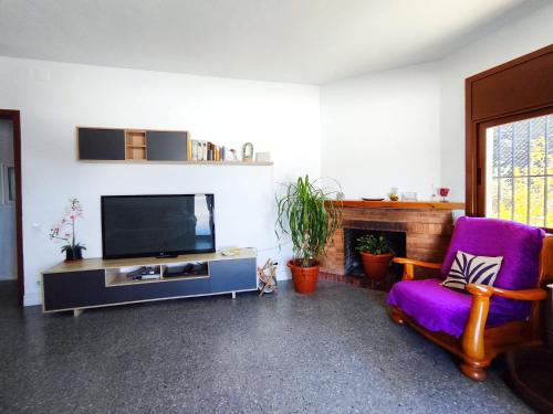 sala de estar con TV y silla morada en Casa con piscina privada en Sant Pol de Mar, en Sant Pol de Mar