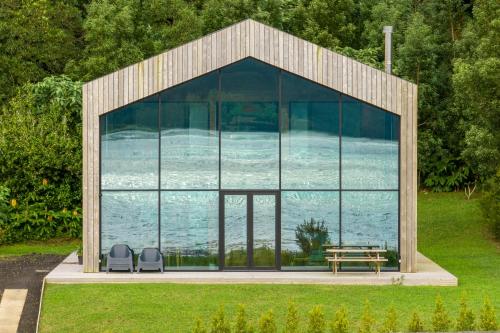 a glass house with two chairs and a table at Sete Cidades Lake Cabin - Casa da Lagoa in Ponta Delgada