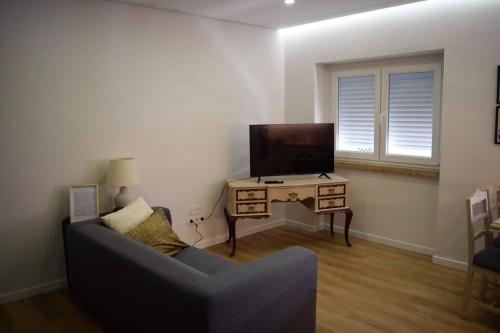 ein Wohnzimmer mit einem Sofa und einem Tisch mit einem TV in der Unterkunft Carlos Place in Vila Franca de Xira