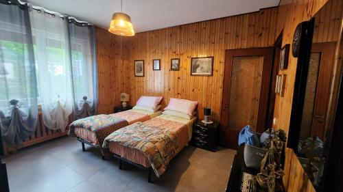 a bedroom with two beds and a window at Casa Paola - Appartamento 2 stanze a Recoaro Terme in Recoaro Terme