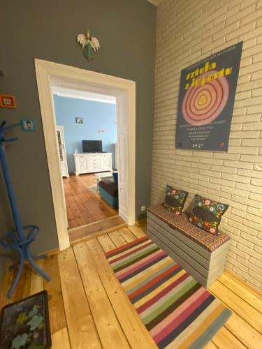 a living room with a rug and a room with a wall at Apartament Kamienica Centrum in Kętrzyn