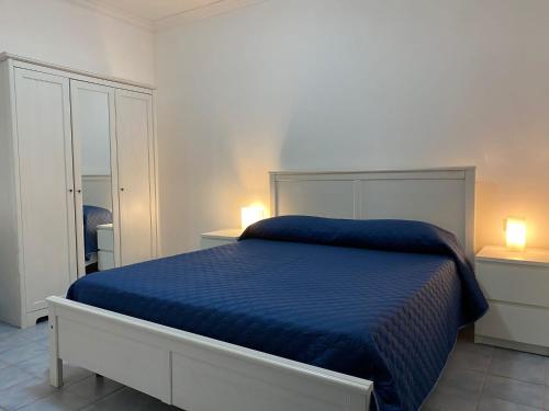 a bedroom with a bed with a blue comforter and two lamps at Residence Eden in Marina di Camerota