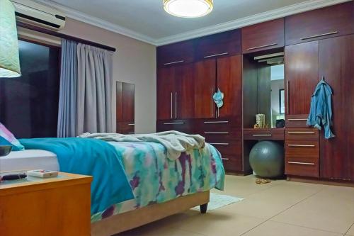 a bedroom with a bed and a dresser and a mirror at Marks Cottages in Durban