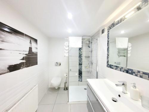 a white bathroom with a shower and a sink at Apartamenty Cudowna Wyspa in Świnoujście