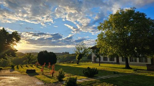 a garden with a building and a sky with clouds at Agriturismo IL FRA' in Tigliole