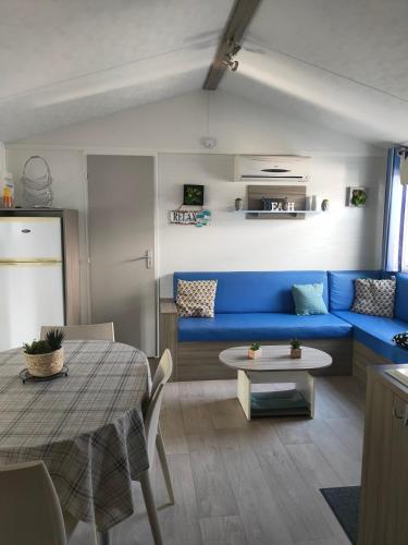 un salon avec un canapé bleu et une table dans l'établissement Logement paisible en camping, à Biscarrosse