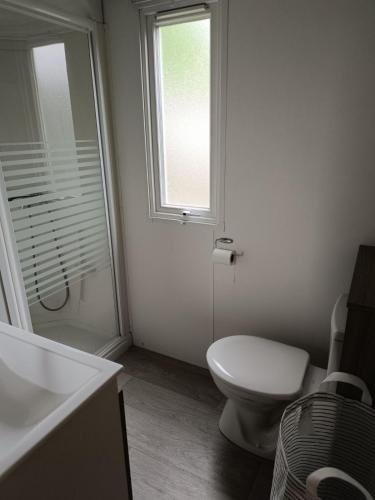 une salle de bain blanche avec toilettes et fenêtre dans l'établissement Logement paisible en camping, à Biscarrosse