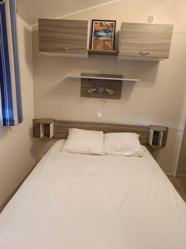 Ce lit se trouve dans une petite chambre dotée d'un lit blanc. dans l'établissement Logement paisible en camping, à Biscarrosse