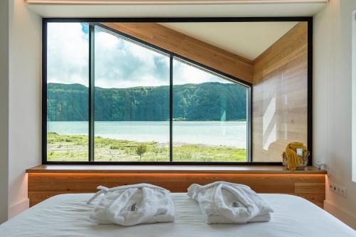 um quarto com uma grande janela com toalhas numa cama em Sete Cidades Lake Cabin - Casa da Lagoa em Ponta Delgada