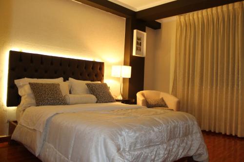 a bedroom with a large bed and a chair at Hotel Venecia in Huánuco
