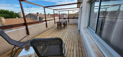 un balcon avec une chaise et une table. dans l'établissement La Terrasse sur les toits du centre ville à 300m de la plage, au Grau-du-Roi