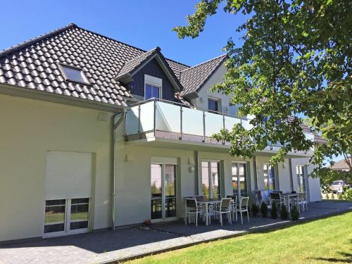 una casa con balcón y mesas y sillas en Haus Sonne - Whg 01 Sandperle, en Thiessow